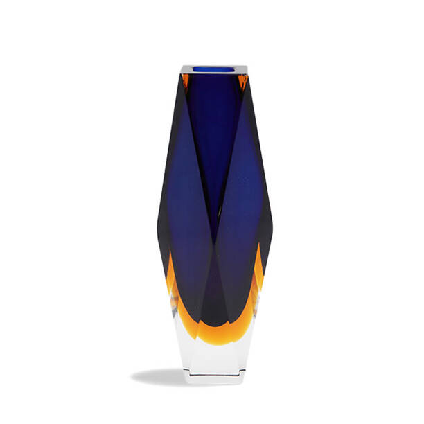 The image features a striking piece of Murano glass art, specifically a vase. It's characterized by its tall and slender form with a slightly flared opening, which suggests it could be used for decorative purposes to hold flowers or other decorative items. The vase is predominantly blue in color, but there are subtle variations that give it depth and complexity—these variations could indicate different shades of blue or even the presence of another color, possibly orange, creating a gradient effect from top to bottom. The craftsmanship appears to be exceptional, with smooth transitions between colors and a reflective surface that suggests a glass-blowing technique was used in its creation. The base of the vase is narrow and solid, providing stability. The overall design is elegant and modern, reflecting both functional artistry and aesthetic value. The image itself has been designed to highlight the product, with a clean white background on one side and a warm tan or beige color on the other, which creates a contrasting backdrop that further emphasizes the vase's vibrant colors and intricate design. The keywords associated with this image include 