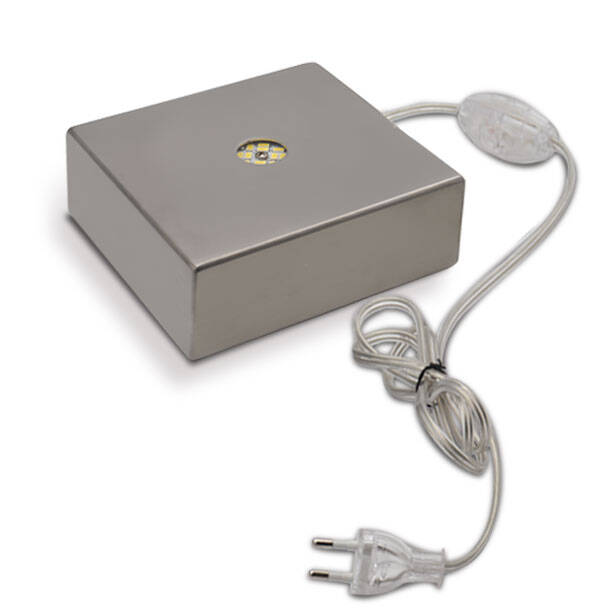 This image shows a product packaging with a corded electrical device. The package appears to be for an Alessandro Mandruzzato item, which is likely related to the Murano glass industry in Venice, Italy, given the context provided. However, there's no visible glassware or lamp that typically represents the famous Venetian glass artisans. Instead, it seems like we are looking at a device that might be used for creating or working with Murano glass, but without further information, its exact function remains unclear. The packaging is predominantly silver and has a small logo on top, which suggests a branded product.