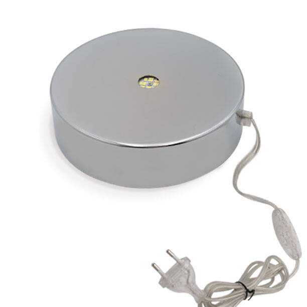 The image shows a round, metallic-looking object with a cord attached to it. The cord has a plug at the end, suggesting that this item is an electrical device or accessory. The design of the object appears sleek and modern, possibly indicating high-end craftsmanship or technology. However, without more context or visual cues, I'm unable to determine what specific function this object serves. If it's related to Murano glass as you mentioned, it could be a product from Alessandro Mandruzzato's factory, known for its quality and design.