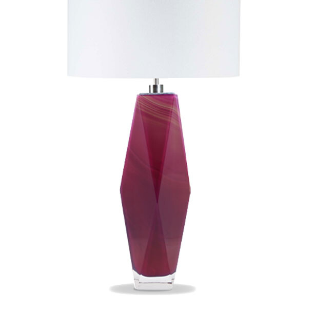 This image features a beautifully crafted lamp with a unique design. The base of the lamp is elongated and appears to be made in shades of red, possibly using a technique that gives it a marbled or layered effect. This color and pattern are reminiscent of Venetian glass artistry, known for its intricate designs and vibrant colors. The lamp has a white lampshade that complements the base, creating a striking contrast between the colorful base and the neutral shade. The design is modern yet elegant, with smooth curves and a substantial feel to it. It seems to be crafted by Alessandro Mandruzzato, as indicated by the text in the image, which suggests this lamp may have been made in Italy, particularly Venice, where such glassmaking techniques are widely known and celebrated. The background is plain and does not distract from the lamp itself, allowing the viewer to focus on its design and details. This style of image is often used for advertising or showcasing products, aiming to highlight the item's features without any additional elements that might compete for attention.