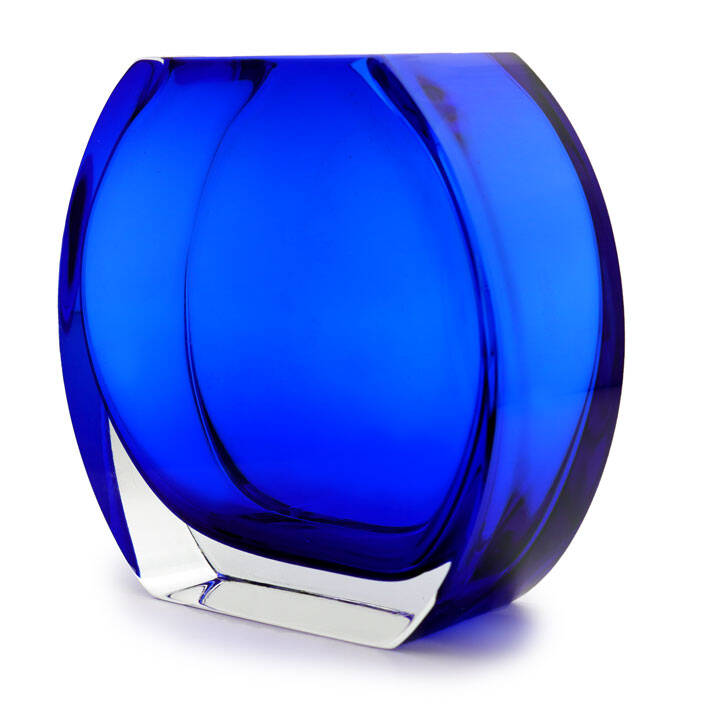 This image showcases a beautifully crafted blue glass vase. The vase has a unique design with vertical ridges that give it an elegant, textured appearance. It is a deep blue color throughout and has a glossy finish that reflects light, highlighting its smoothness. At the top of the vase, there's a silver-toned rim which contrasts with the dark hue of the glass and adds a touch of sophistication. The base also appears to be made from metal, complementing the overall design. The vase is set against a neutral background that does not distract from the item itself. It looks quite substantial in size, suggesting it could hold a good amount of flowers or decorative branches. The craftsmanship and coloration suggest this might be a piece of Murano glass, which is known for its vibrant hues and intricate designs, often associated with Italian artisanal traditions. This particular piece would likely appeal to those interested in high-quality glassware and home decor.